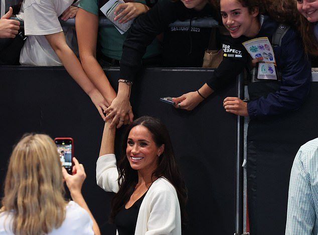 Beaming Meghan dashes to take a snap with fans chanting ‘Sussex Squad is here’ – before she and Harry pose with Invictus Games athletes